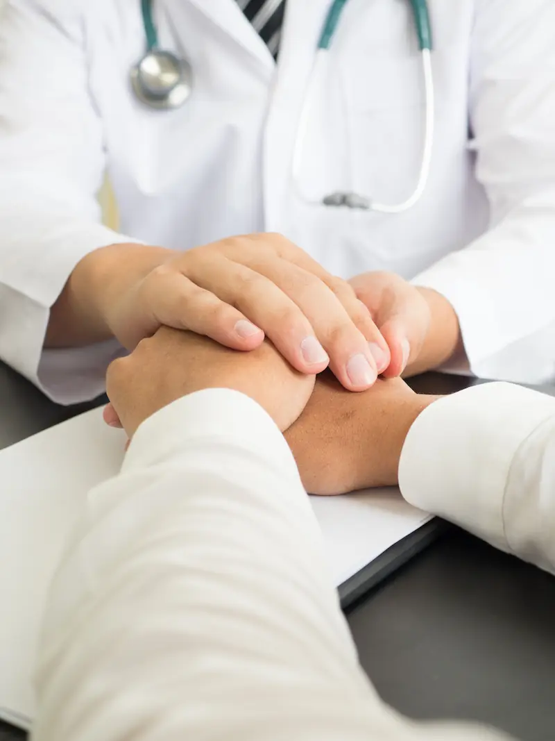 Un médico sostiene las manos de un paciente en un gesto de apoyo y empatía